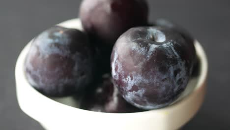 close up of plums in a white bowl