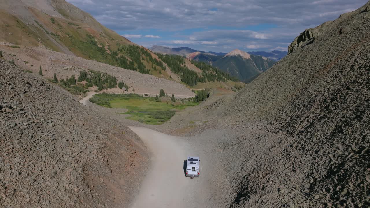 Il Passo Ophir si apre su un terreno alpino ondulato, mentre la strada stretta passa da ripide scogliere a paesaggi di alta montagna più ampi vicino a Telluride, Colorado.