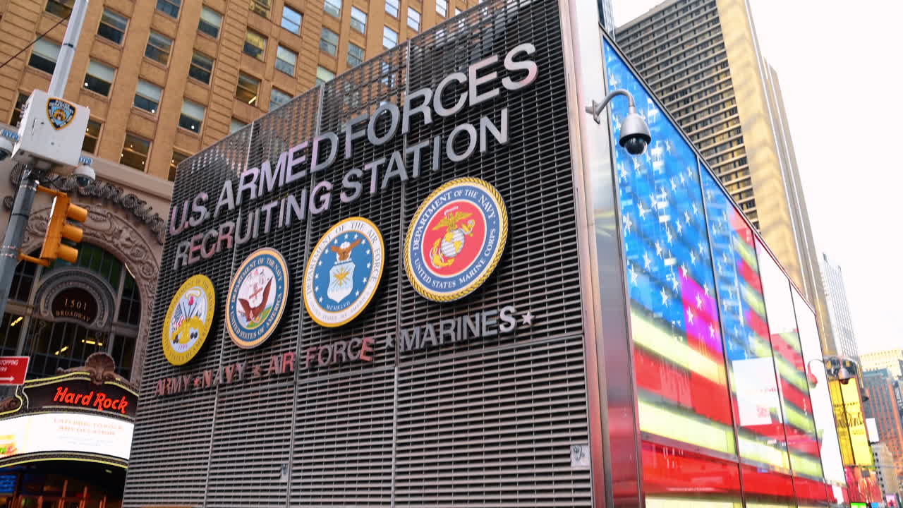 New York, USA, 1 agosto 2025: stazione di reclutamento delle forze armate statunitensi a Times Square, Manhattan, New York. Insegna con i simboli dell'esercito, della marina, dell'aeronautica e dei marine da una prospettiva dal basso