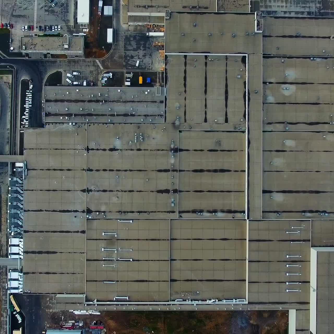 Industrial plant. Huge territory of a factory. Roofs of industrial buildings. Car parking near manufacture. Camera rising. Top aerial view.