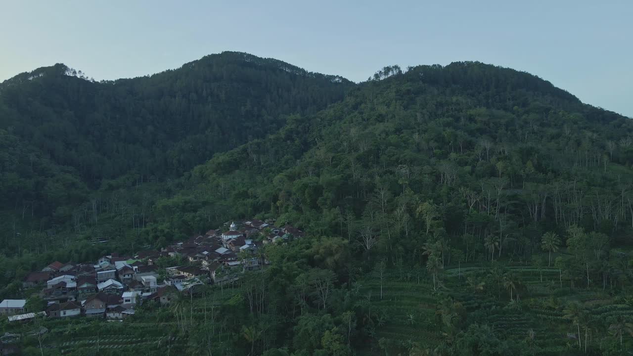 vista aérea de la aldea al pie de la colina boscosa por la mañana