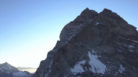 aerial view of the matterhorn from drone descending with rugged landscape, steep cliffs, snow and ice on mountain