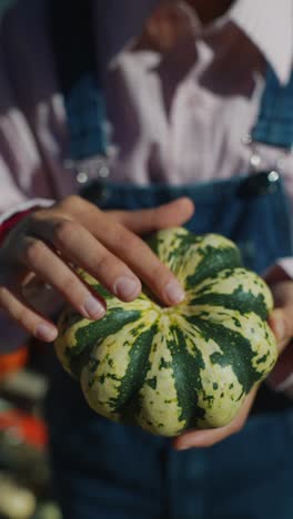 person holding a striped pumpkin