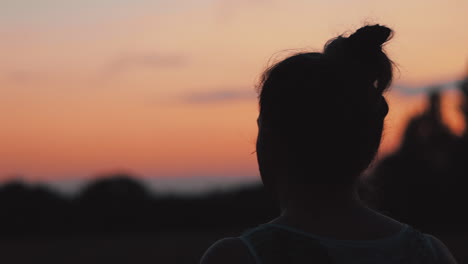 órbita detrás de la mujer mirando la puesta de sol en el campo, tiro medio, borehamwood, hertfordshire, reino unido