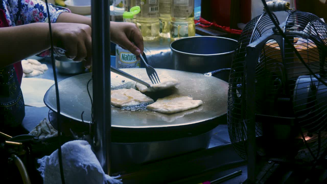Rekaman masakan sinematik 4K seorang koki Thailand menyiapkan hidangan penutup tradisional Thailand bernama Roti di pasar jalanan di Thailand