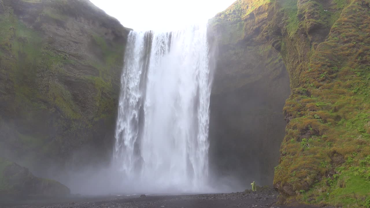 un hombre camina cerca de la cascada de skogafoss en islandia