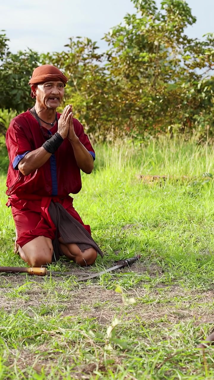 Artista marziale thailandese inginocchiato in abito tradizionale con spada