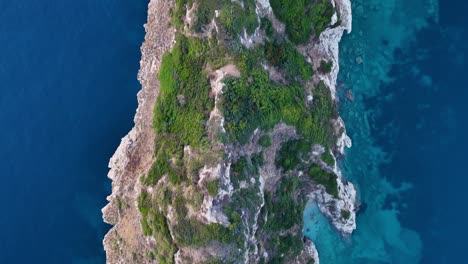 aerial perspective of rugged cliffs, lush greenery, and deep turquoise waters