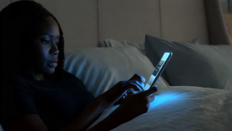 woman using a phone in bed at night