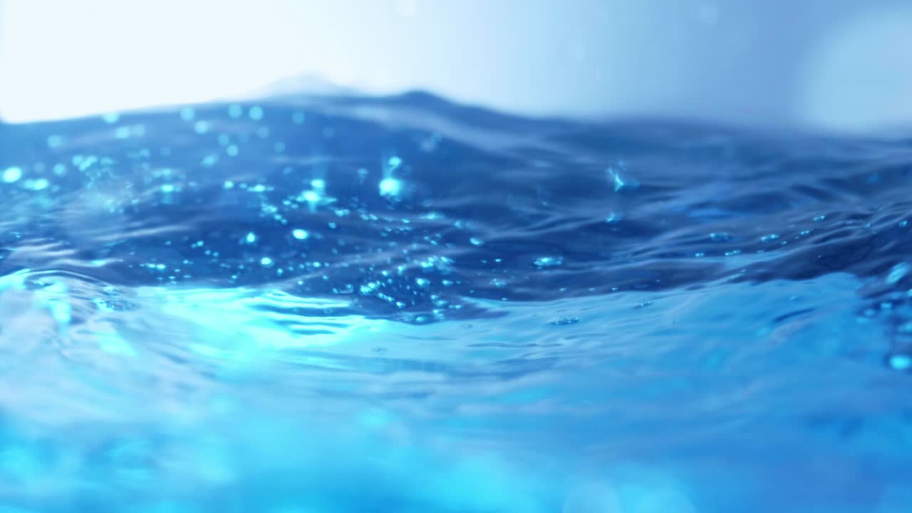 슬로우 모션의 깨끗한 물 표면은 물이 튀는 상점으로 화면을 채우고 기포로 액체 표면을 흔들고 있습니다.