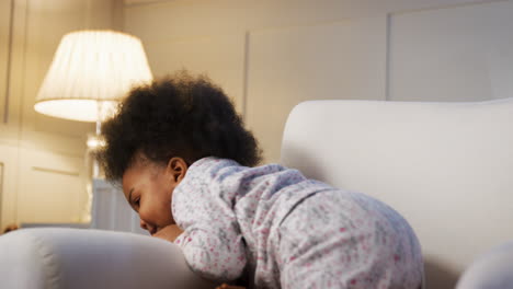 Laughing-Male-Toddler-Sitting-In-Nursery-Chair-At-Bedtime