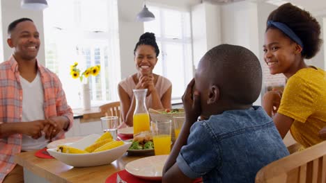 Vista-Frontal-De-Una-Familia-Negra-Feliz-Comiendo-En-La-Mesa-Del-Comedor-En-Una-Casa-Cómoda-4k