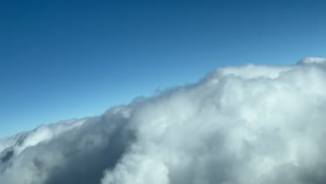 escena de nubes, desde la perspectiva de los pilotos, filmada durante un vuelo en tiempo real a través de un cielo nublado con un cielo azul profundo