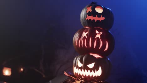 Video-of-halloween-carved-pumpkins-and-smoke-with-copy-space-on-blue-background