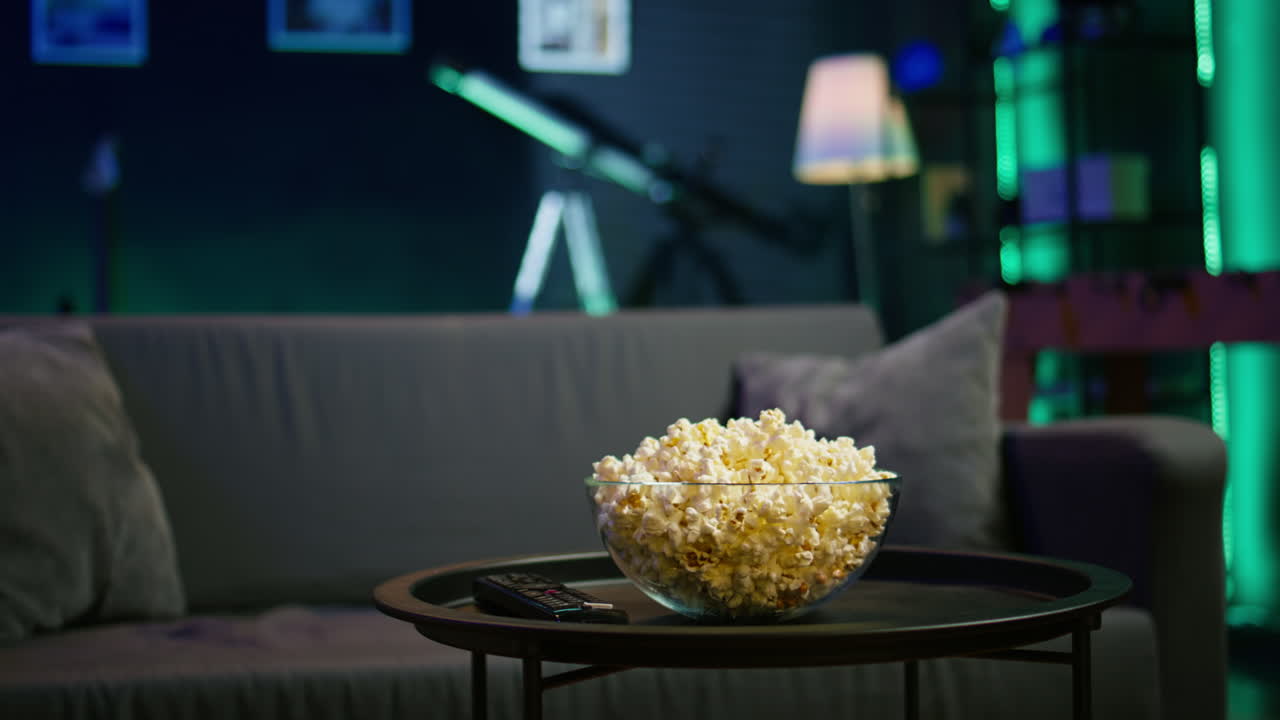 空のネオンで照らされた居心地の良い住宅内装のテーブルの上のポップコーン鉢