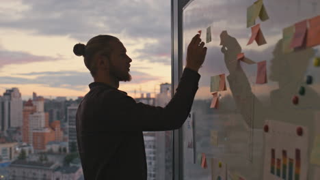 Man-silhouette-attaching-stickers-sunset-office-closeup.-Two-people-taking-break