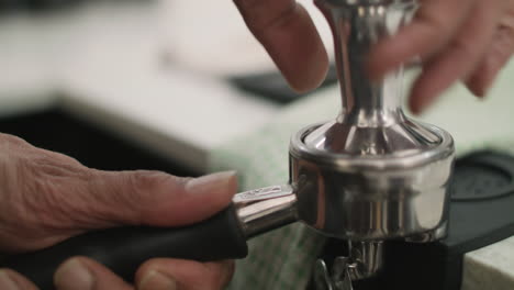 Close-up-of-coffee-grounds-being-tampered-in-a-portafilter