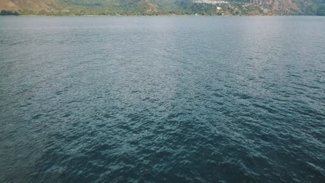 Drone-aerial-flyover-revealing-the-blue-lake-Atitlan,-Guatemala