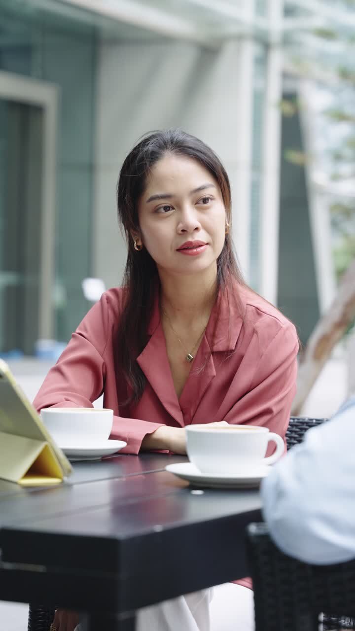 A woman having coffee at an outdoor cafe with a tablet