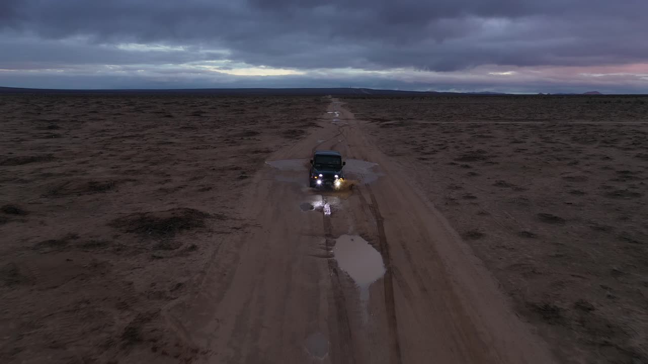 화려한 하늘과 함께 일몰에 폭우가 내린 직후 모하비 사막을 통해 지프차를 몰고