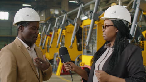 female tv journalist interviewing factory manager