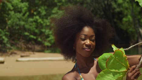 disfrutando de un día soleado, una chica con cabello rizado se pone un bikini en una playa tropical de una isla del caribe de cerca