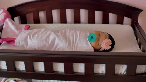 a newborn baby wrapped in a blanket, laying in a crib in a nursery