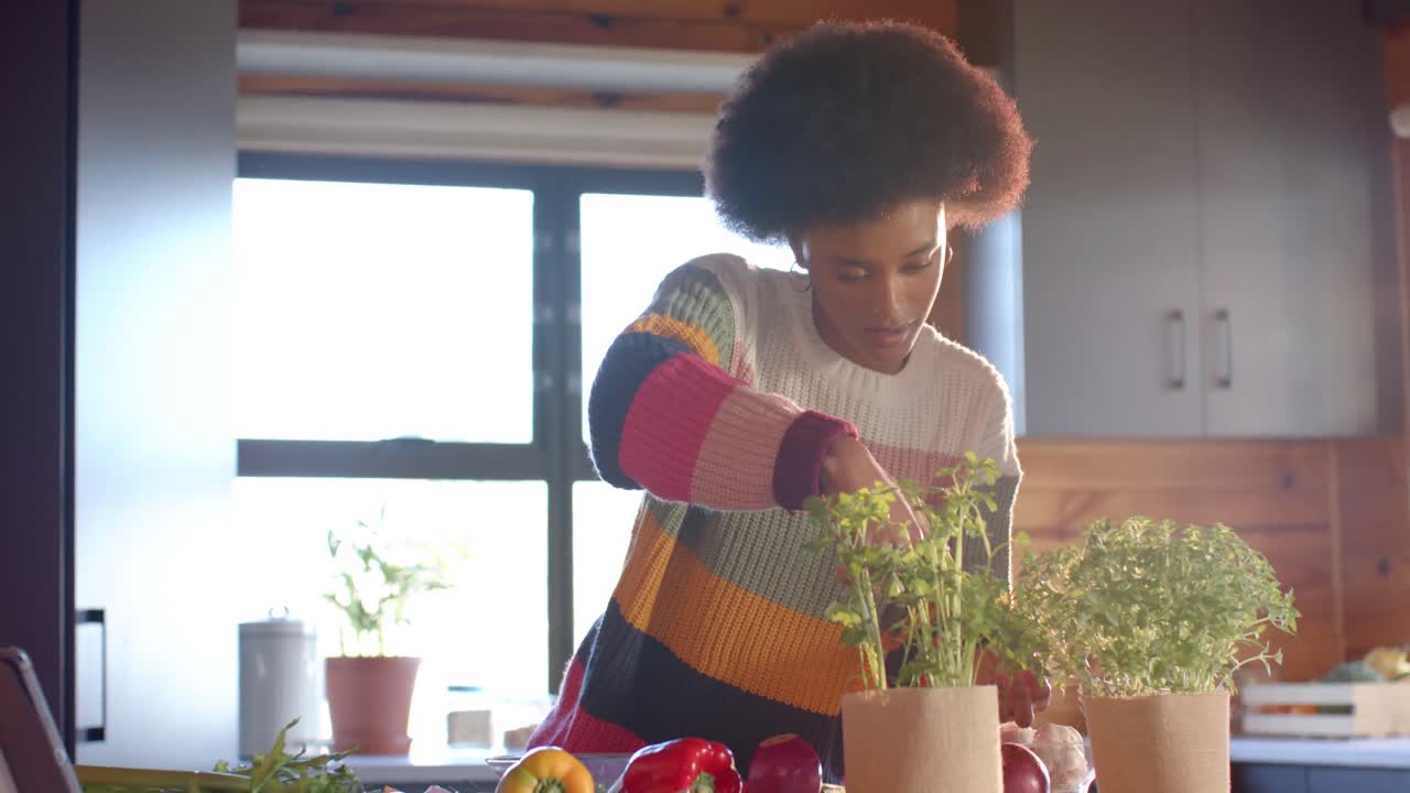 Mulher negra preparando uma refeição em uma cozinha ensolarada, em câmera lenta.