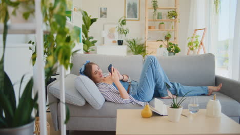 teenage girl browsing smartphone on sofa