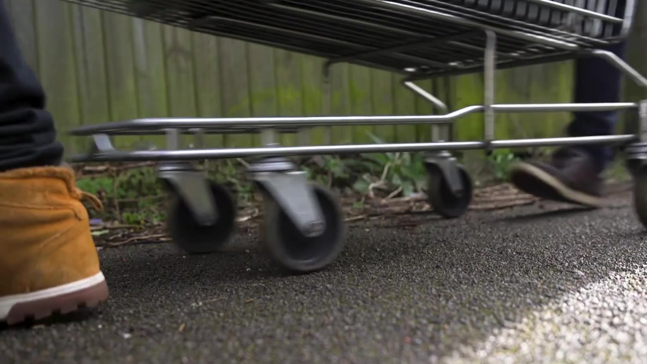 Inquadratura dal basso di un carrello della spesa spinto da due uomini