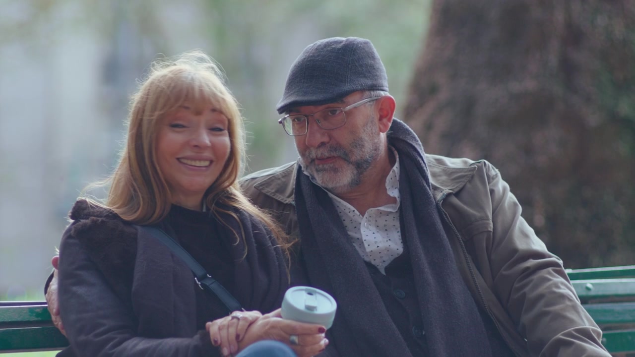 Happy Senior Couple Sitting on Bench in the Park and Chatting