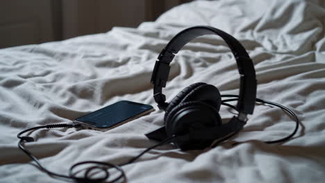 headphones and smartphone on a bed