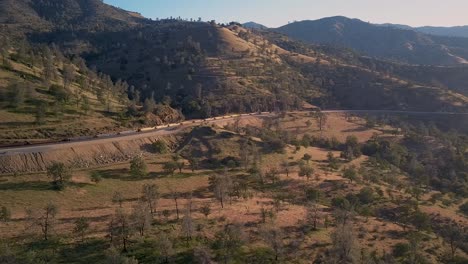 Train-moving-past-Sierra-Nevada-mountains-in-Tehachapi,-California-at-golden-hour