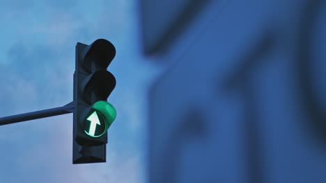 a traffic light on the background of a cloudy sky is lit in green. arrow indicating movement. out of focus road sign in the foreground. arrow indicating movement