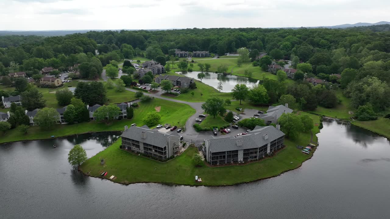 Apartment Buildings at cul-du-sac in american suburb. Aerial wide shot. River access in american suburb. Cloudy day in forest landscape.