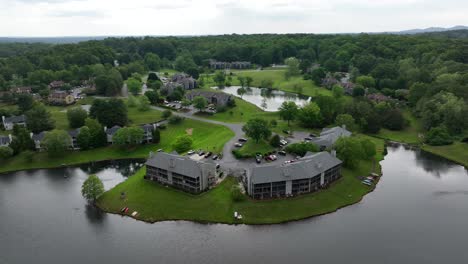apartment buildings at cul-du-sac in american suburb. aerial wide shot. river access in american suburb. cloudy day in forest landscape.