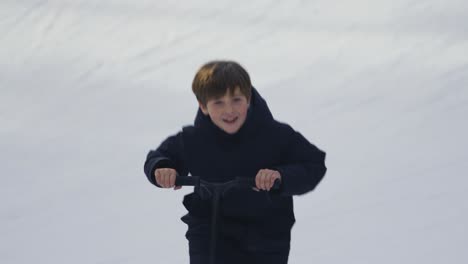 a laughing boy on a snow scooter rides towards the camera