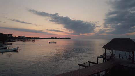 Tulum-pink-sunset-aerial-of-beautiful,-relaxing-dock-on-the-sea,-fishing-boats-drifting,-Mexico