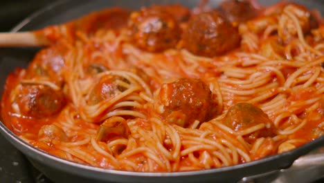 delicious italian meatballs with spaghetti pasta absorbing flavour of rich tomato sauce with pepper and herbs as camera rotates in slow motion. homemade cooking food footage.