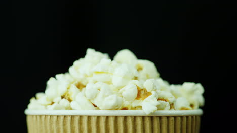 un bicchiere di carta di popcorn ruota lentamente e senza intoppi su un video 4k di sfondo nero