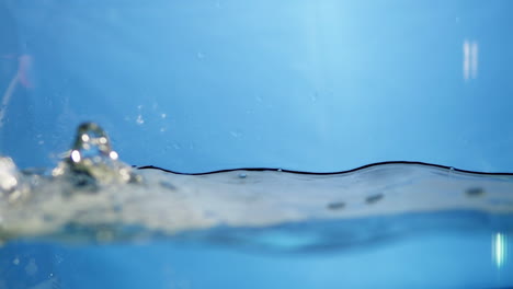 Makroansicht-Der-Strömungsdynamik-Von-Süßwassertropfen-In-Bewegung,-Symphonie-Der-Natur,-Zeitlupen-Wasserkräuseleffekt-In-Blauem-Farbton