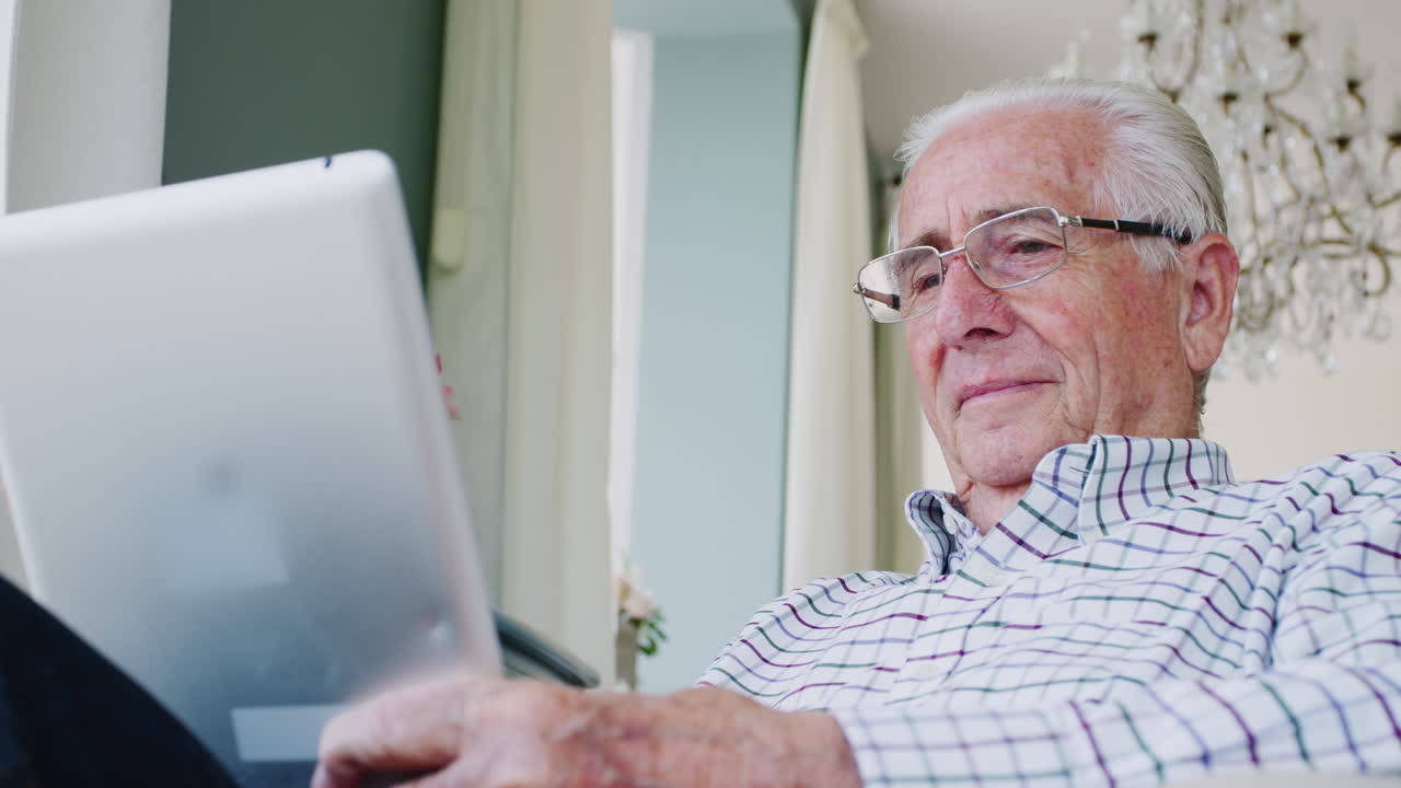 Happy senior man using tablet computer at home, close up