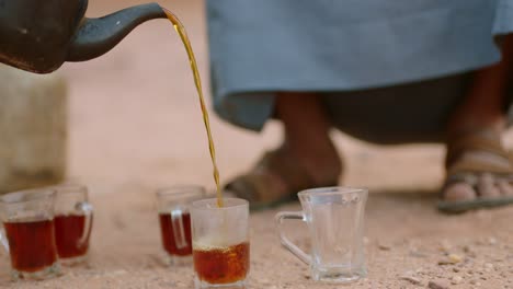 Tea-is-poured-into-glass-cups-on-the-ground