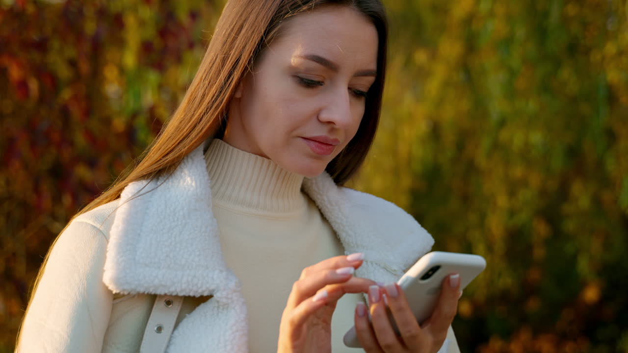 mujer usando el teléfono en el parque de otoño