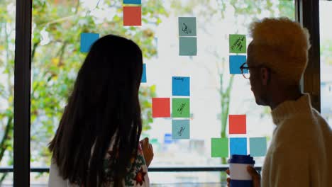 rear view of young mixed race business colleagues discussing over sticky notes in modern office 4k