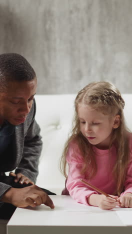 african-american male teacher writes word by finger on table and children try to guess during home lesson with english native speaker slow motion