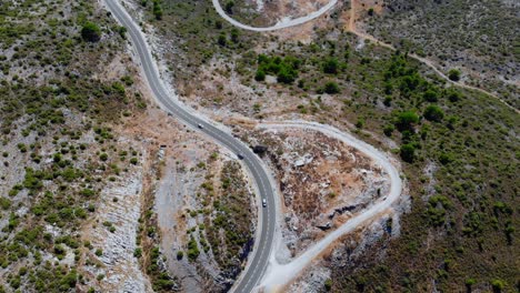 Drone-shot-of-some-cars-driving-on-a-road-in-the-nature-across-the-terrain-in-Andalusia,-Spain