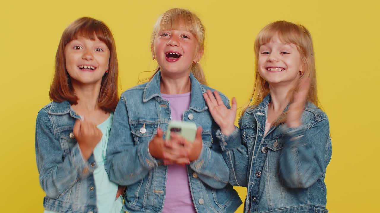 Three girls siblings friends use smartphone celebrate playing online game great big win good news
