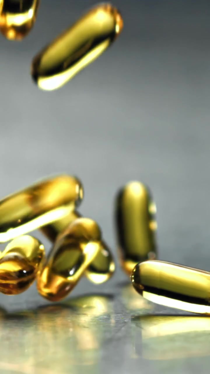 Capsule softgel dorate che cadono e rimbalzano al rallentatore