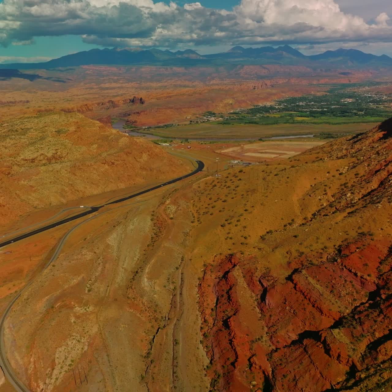 Rocks, deserts and green valleys in the national park of Utah. Drone flying over the motorway at the foot of canyon. Aerial perspective